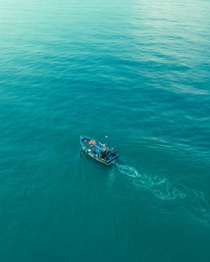 A serene aerial view of a lone boat sailing on the vast Indian Ocean near Goa.