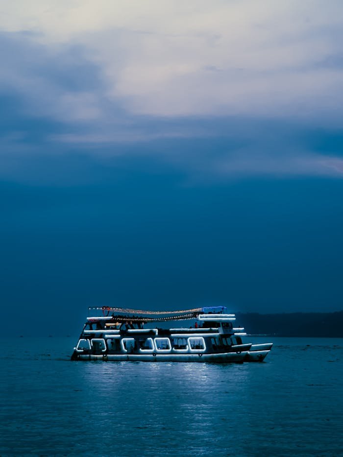 Serene boat cruising on calm waters under a twilight sky in Panaji, India.