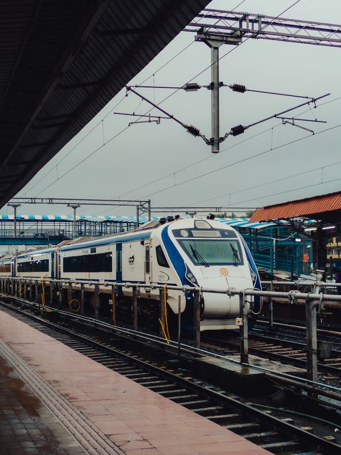 Modern train approaching Madgaon station platform on a cloudy day in India.